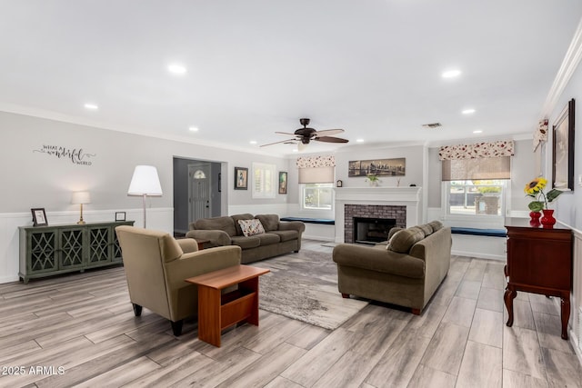 living room with crown molding, a fireplace, and light wood-type flooring