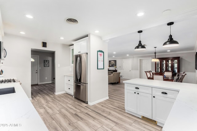 kitchen with white cabinetry, stainless steel appliances, light stone countertops, and pendant lighting