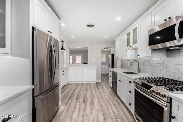 kitchen featuring stainless steel appliances, white cabinetry, and sink