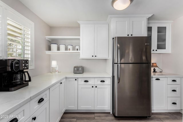 kitchen with stainless steel fridge, light stone countertops, and white cabinets