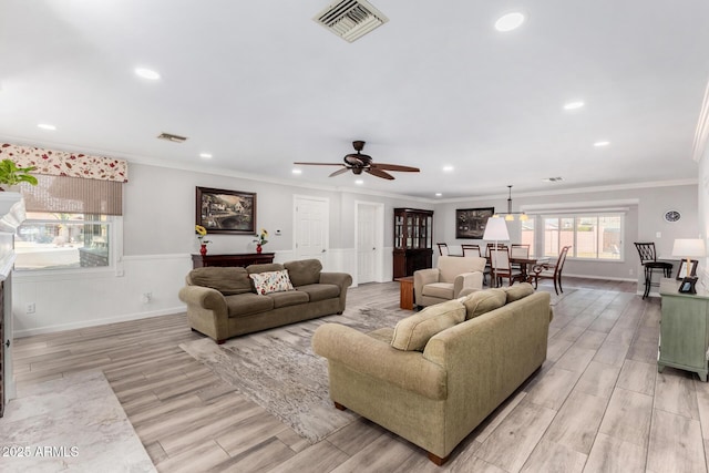 living room with crown molding, ceiling fan, and light hardwood / wood-style flooring