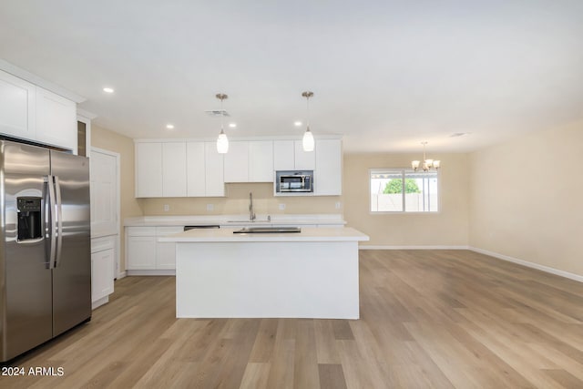 kitchen featuring pendant lighting, stainless steel appliances, white cabinetry, and an island with sink