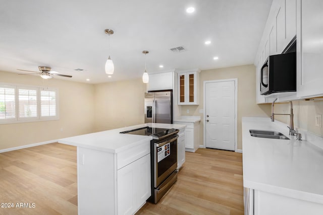 kitchen featuring a kitchen island, stainless steel appliances, hanging light fixtures, and white cabinetry