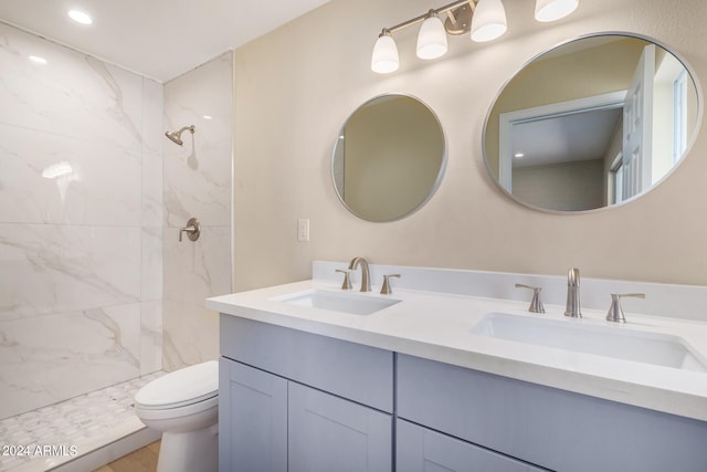 bathroom featuring toilet, vanity, and tiled shower