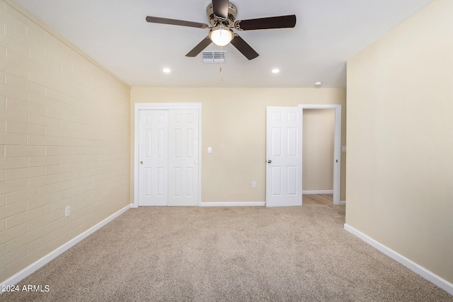 unfurnished bedroom with a closet, carpet, ceiling fan, and brick wall