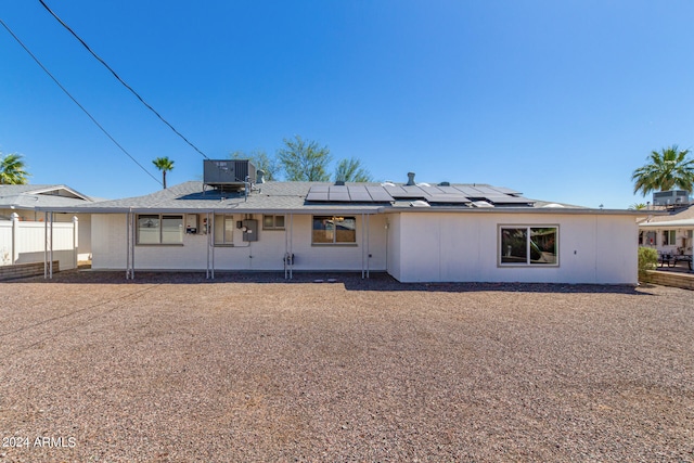 rear view of property with central AC unit and solar panels