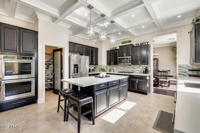 kitchen featuring a kitchen island, stainless steel appliances, light countertops, beamed ceiling, and dark cabinets