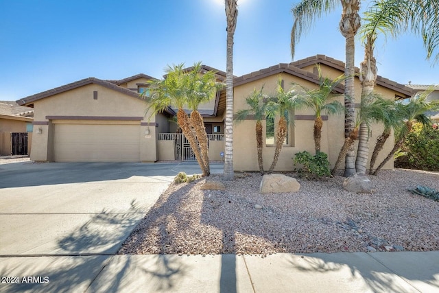 view of front of property featuring a gate, driveway, an attached garage, stucco siding, and a tiled roof