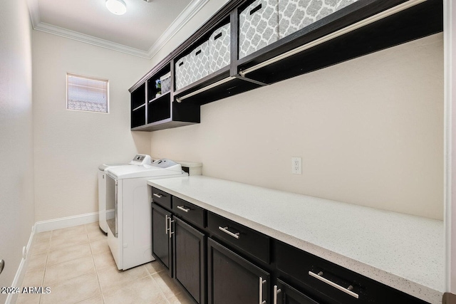 washroom with baseboards, light tile patterned flooring, cabinet space, crown molding, and washer and clothes dryer