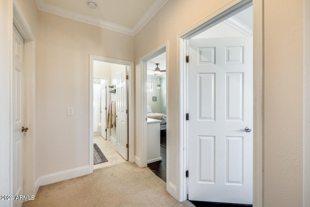 hallway featuring light carpet, crown molding, and baseboards