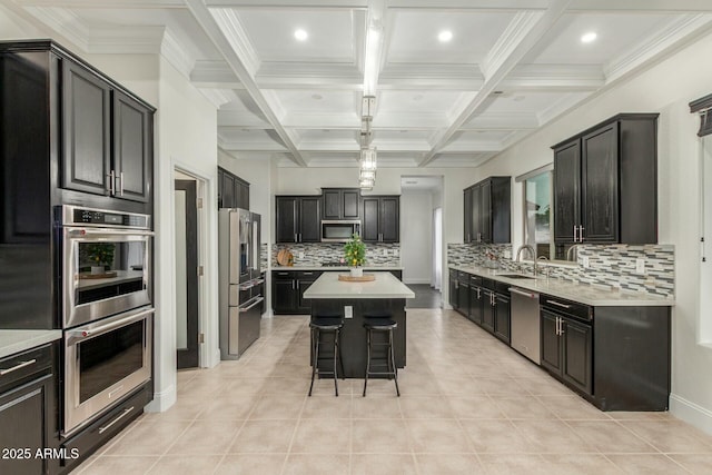 kitchen featuring coffered ceiling, appliances with stainless steel finishes, a kitchen island, and light countertops