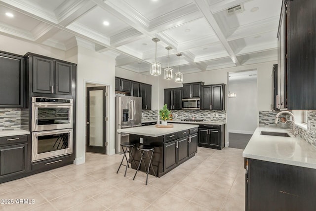 kitchen with beamed ceiling, a breakfast bar, a sink, a center island, and stainless steel appliances