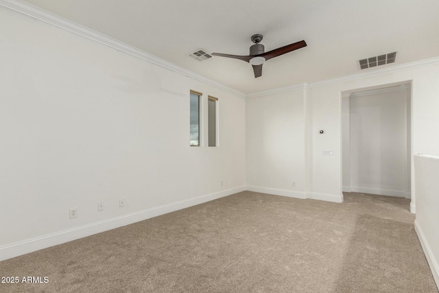 empty room with crown molding, a ceiling fan, visible vents, and light carpet