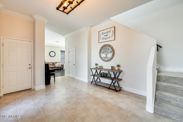 foyer entrance featuring light tile patterned floors, stairway, baseboards, and crown molding