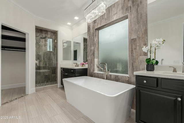 full bathroom featuring a freestanding tub, two vanities, a stall shower, a sink, and crown molding