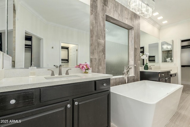 full bathroom featuring a walk in closet, a freestanding tub, vanity, and ornamental molding