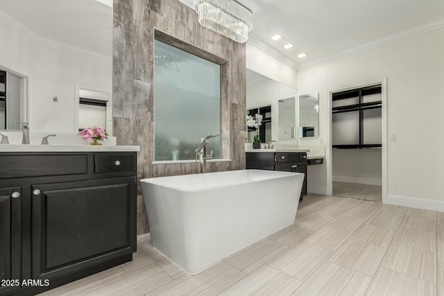 bathroom featuring a freestanding bath, vanity, baseboards, and ornamental molding