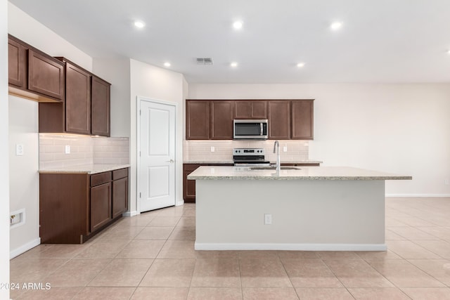 kitchen featuring appliances with stainless steel finishes, a center island with sink, light tile patterned floors, and sink