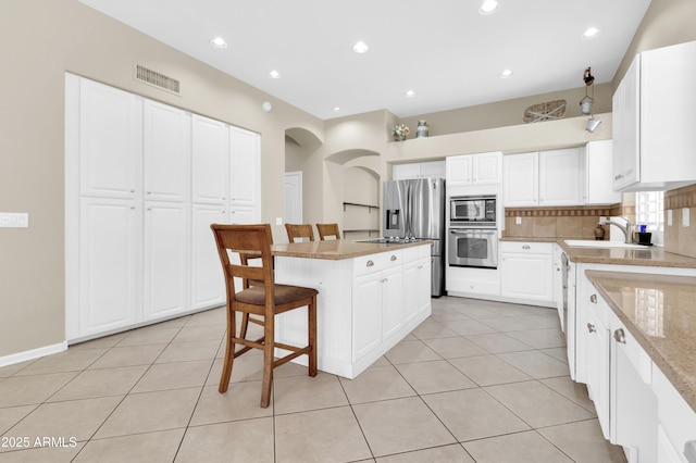 925 W San Marcos Dr, Chandler, AZ 85225 - kitchen with stainless steel appliances, a breakfast bar, light tile patterned floors, tasteful backsplash, and light stone countertops