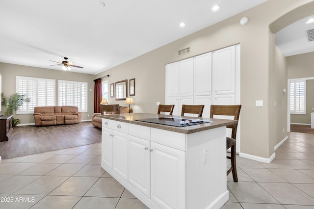 925 W San Marcos Dr, Chandler, AZ 85225 - kitchen featuring black electric stovetop, a kitchen bar, light tile patterned floors, a center island, and ceiling fan