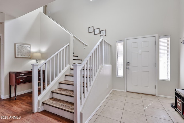 entrance foyer with baseboards, light tile patterned floors, stairway, and a healthy amount of sunlight