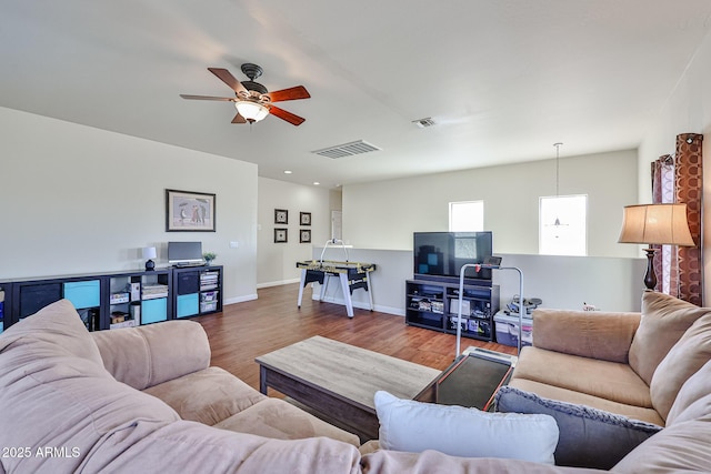 living area featuring a ceiling fan, baseboards, visible vents, and wood finished floors