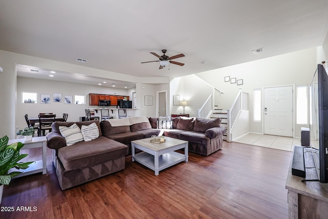 living area with stairs, visible vents, and wood finished floors