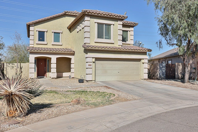 mediterranean / spanish home with a garage, fence, concrete driveway, a tiled roof, and stucco siding