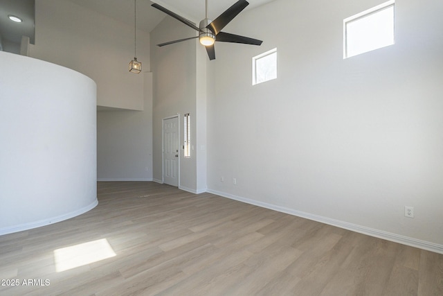 unfurnished room featuring ceiling fan, light hardwood / wood-style flooring, and a towering ceiling