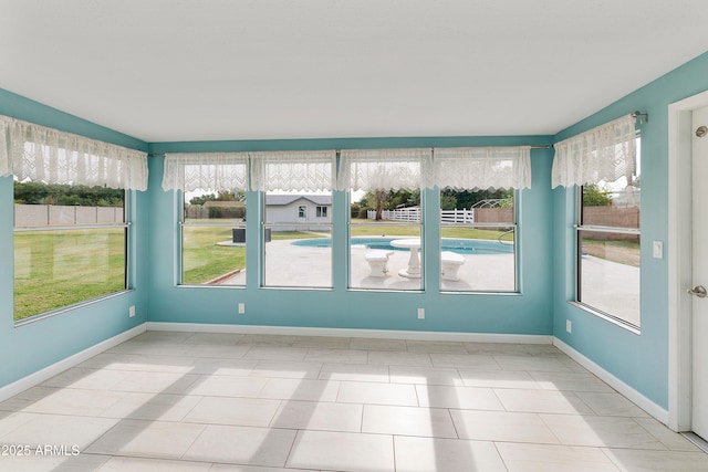 unfurnished sunroom with plenty of natural light, baseboards, and tile patterned floors