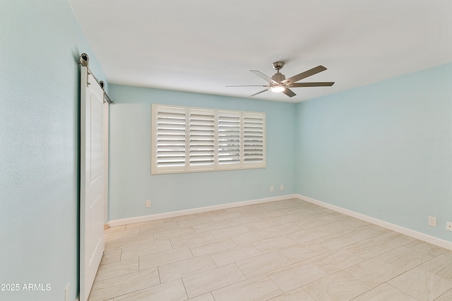 unfurnished room with a barn door, baseboards, and ceiling fan