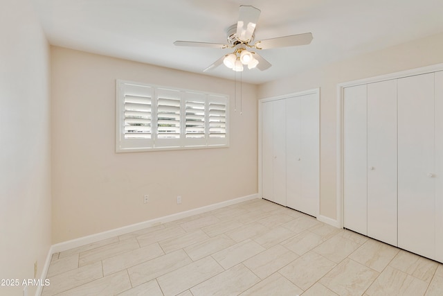 unfurnished bedroom with ceiling fan, baseboards, and two closets