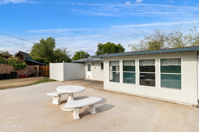back of property featuring stucco siding, fence, and a patio