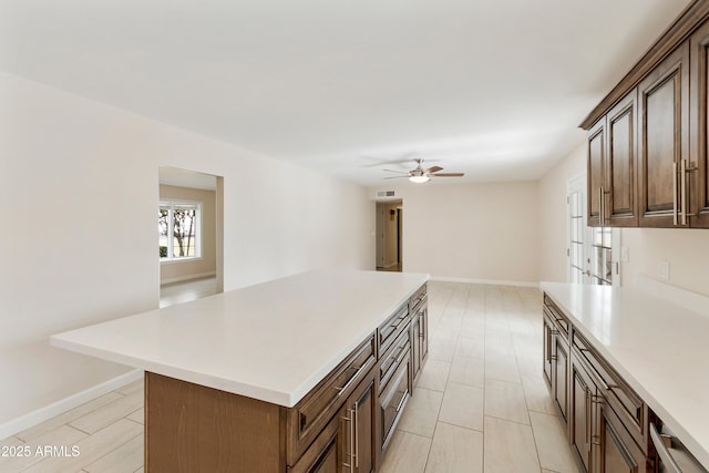 kitchen featuring light countertops, visible vents, a center island, baseboards, and ceiling fan