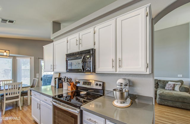 kitchen featuring light wood finished floors, visible vents, black microwave, stainless steel electric stove, and white cabinetry