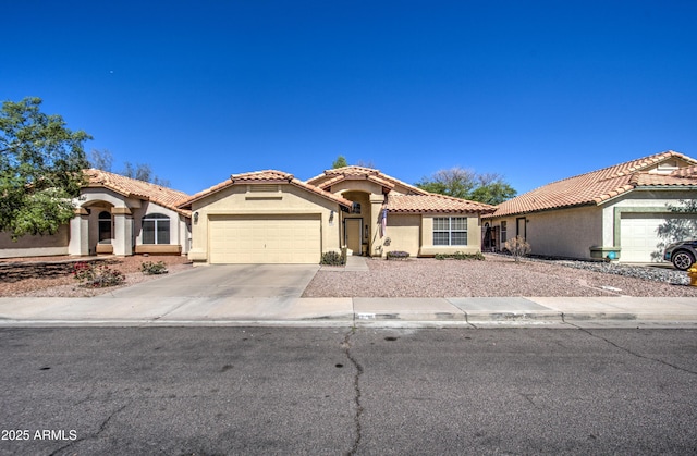 mediterranean / spanish home featuring a tile roof, concrete driveway, a garage, and stucco siding