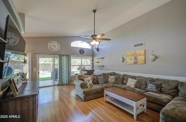 living area featuring a ceiling fan, visible vents, light wood finished floors, and high vaulted ceiling