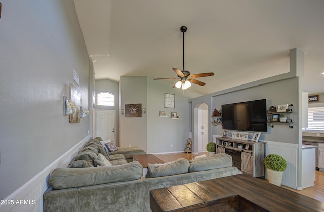 living room featuring arched walkways, dark wood-style floors, baseboards, and ceiling fan