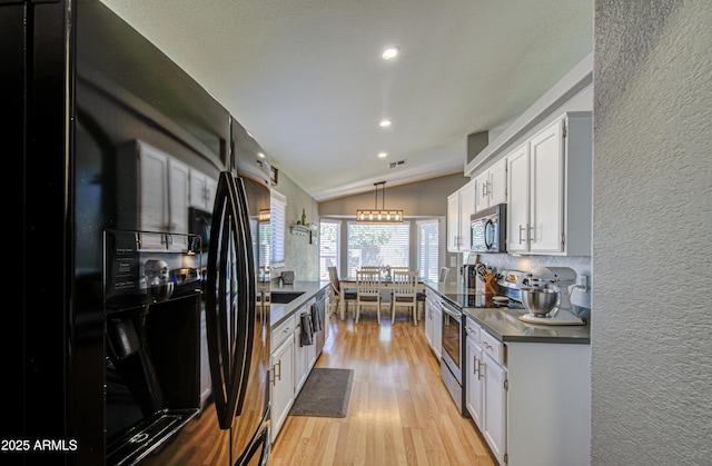 kitchen featuring lofted ceiling, black appliances, white cabinetry, a textured wall, and light wood-type flooring