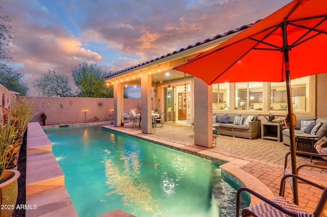 pool at dusk featuring a fenced in pool, a patio area, a fenced backyard, and an outdoor hangout area