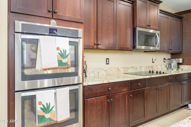 kitchen featuring stainless steel appliances, dark brown cabinetry, and light stone counters