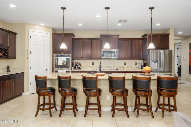 kitchen with visible vents, an island with sink, dark brown cabinetry, and stainless steel appliances