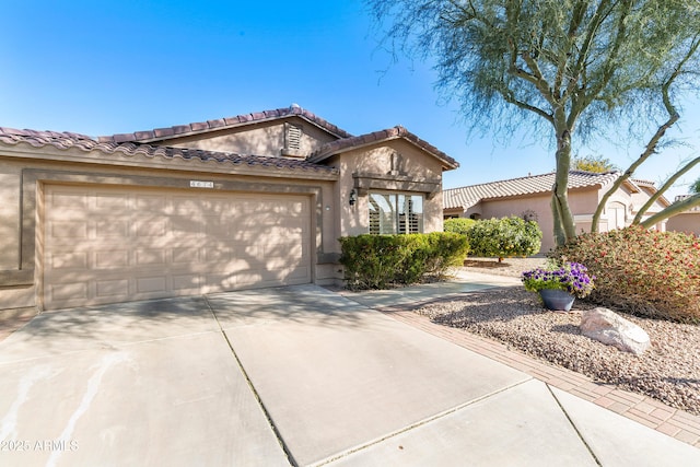 view of front of property with a garage, concrete driveway, a tiled roof, and stucco siding