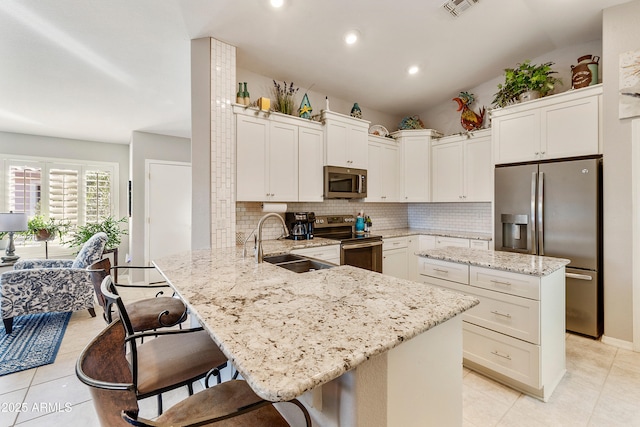 4674 E Alfalfa Dr, Gilbert, AZ 85298 - kitchen with decorative backsplash, a peninsula, stainless steel appliances, a kitchen bar, and a sink
