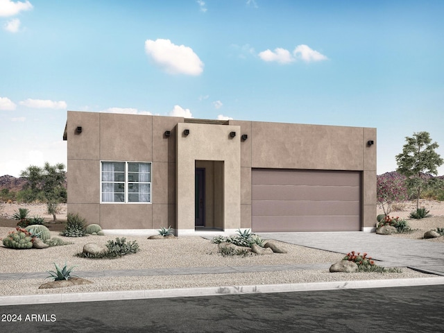 pueblo-style house featuring a garage, driveway, and stucco siding