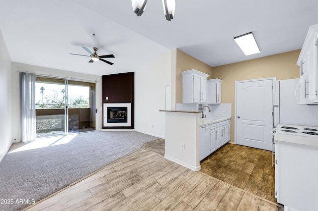 kitchen with white appliances, ceiling fan with notable chandelier, sink, light hardwood / wood-style flooring, and white cabinets