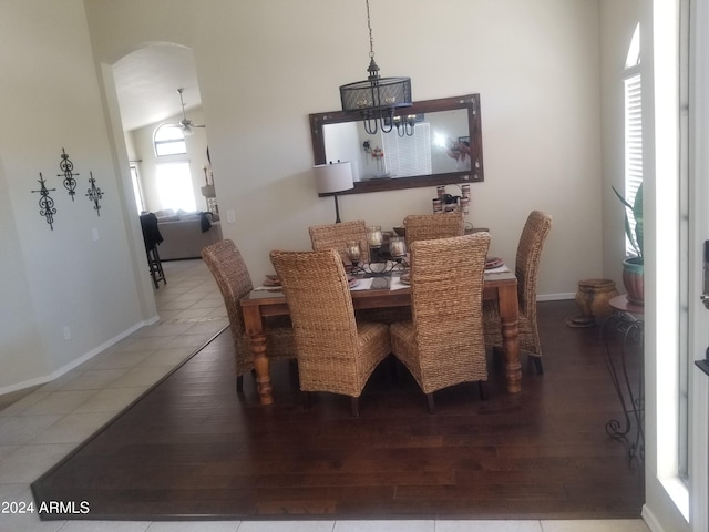 tiled dining area with ceiling fan with notable chandelier