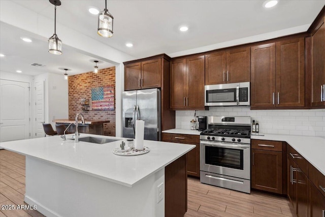 kitchen featuring visible vents, light countertops, a sink, light wood finished floors, and appliances with stainless steel finishes