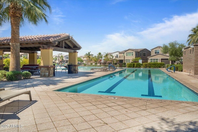 pool with a patio, a residential view, and a gazebo