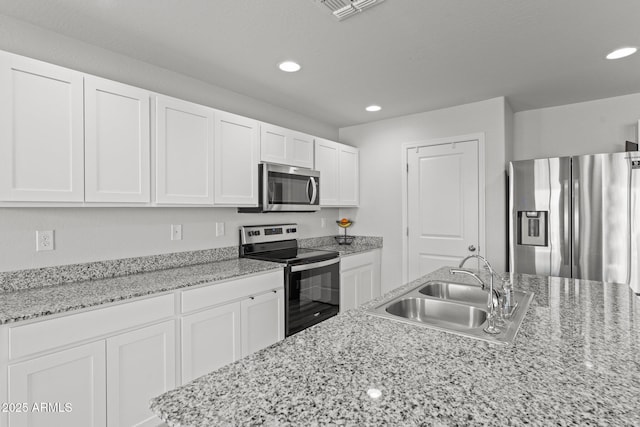 kitchen featuring light stone counters, stainless steel appliances, white cabinetry, and sink